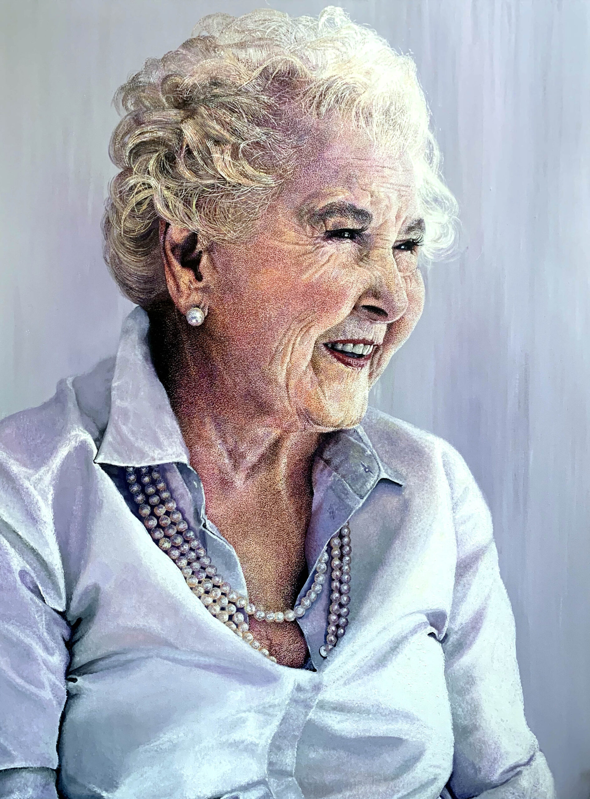 A portrait painting of an older woman wearing a silk shirt and a string of pearls. She is smiling , her cheeks are slightly flushed and there is a delicate purple light in the painting.